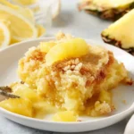 Delicious lemon pineapple dump cake served with a scoop of whipped cream.