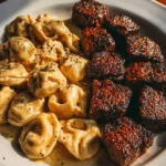 Garlic butter steak bites served with creamy Alfredo tortellini on a plate.