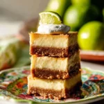 Delicious Key Lime Cheesecake Bars garnished with lime slices and whipped cream.