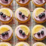 Lemon cookies topped with blueberry frosting on a plate