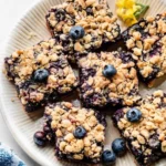Blueberry pie bars topped with fresh blueberries and a crumbly crust