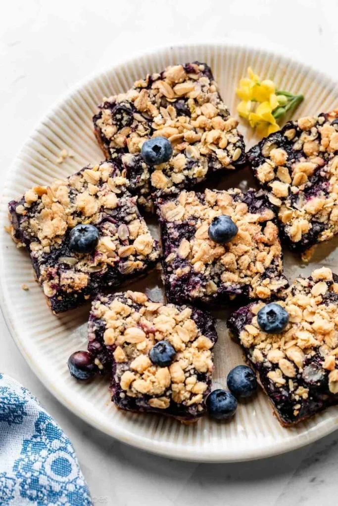 Blueberry pie bars topped with fresh blueberries and a crumbly crust