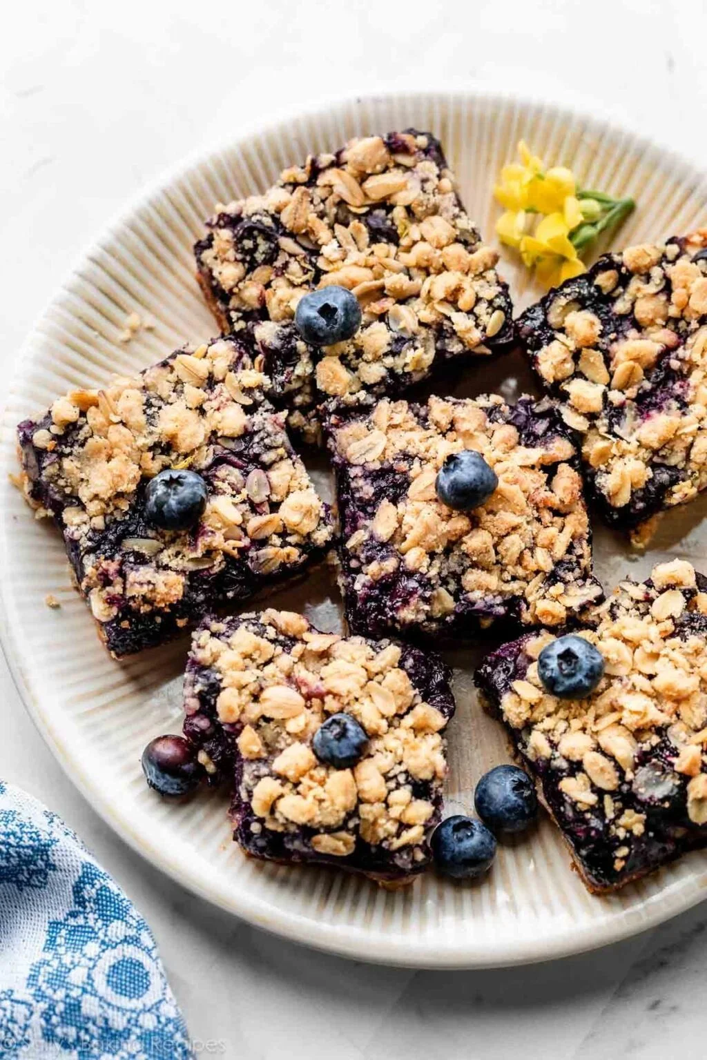 Blueberry pie bars topped with fresh blueberries and a crumbly crust